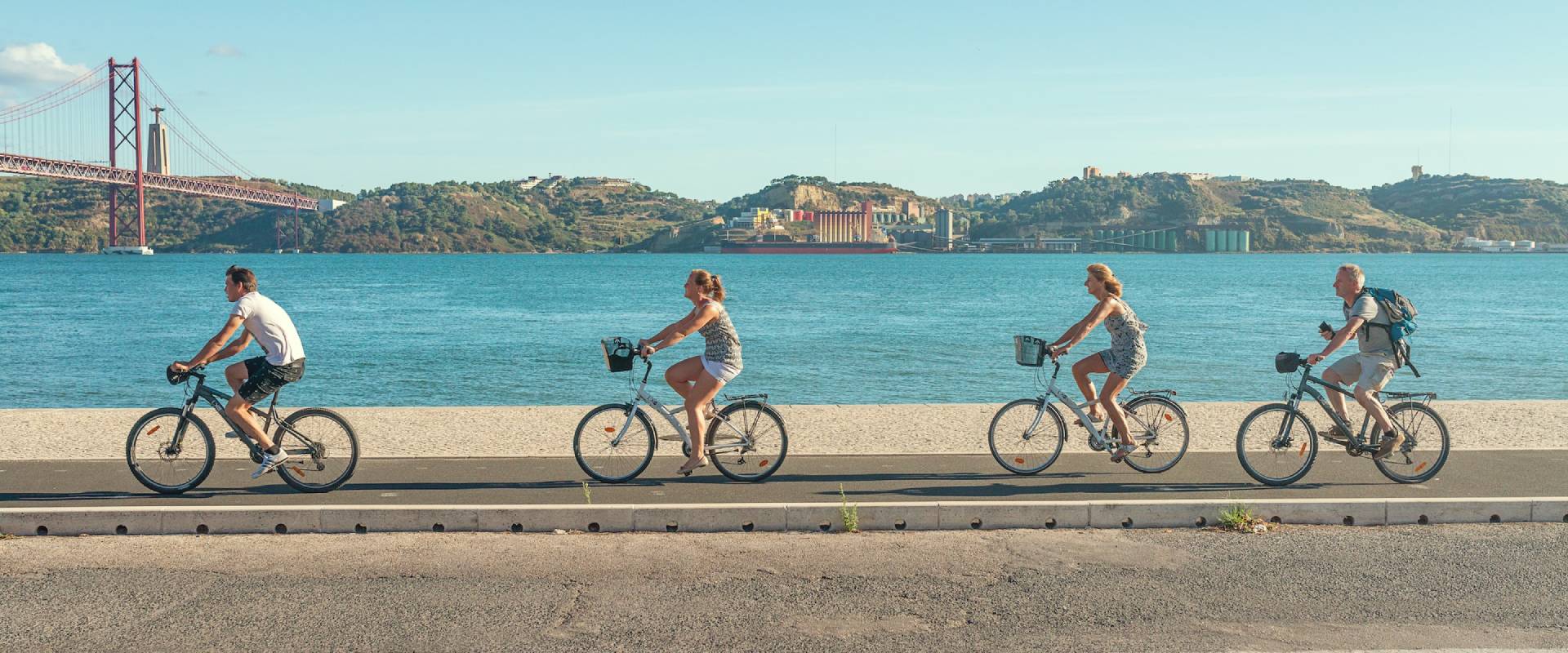 people riding bikes with a bridge behind them